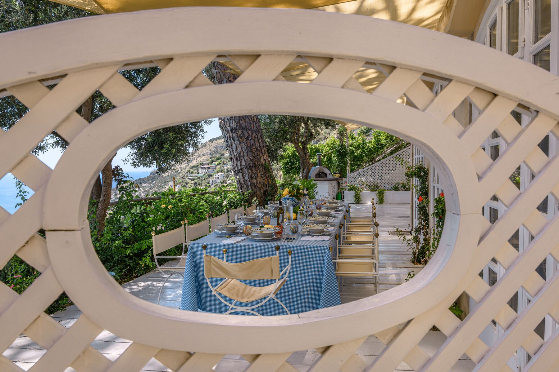 A table set under the pergola of the villa, facing the coast